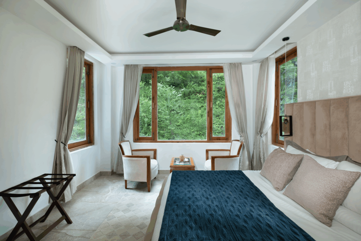 Riverside luxury room with comfortable bed, forest views, and natural light in Tirthan Valley